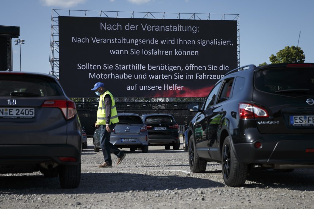 Auf der Abstellfläche eines Autokinos bewegt sich ein Einweiser zwischen den Autos