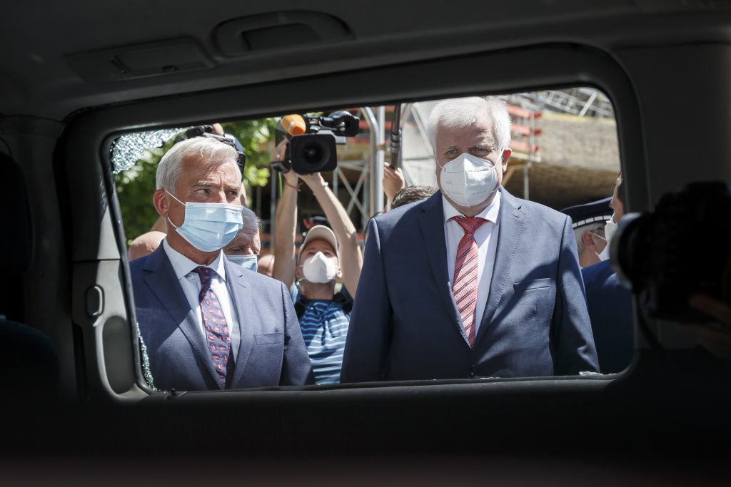 Die Innenminister Horst Seehofer und Thomas Strobl blicken durch die Scheibe eines demolierten Streifenwagens