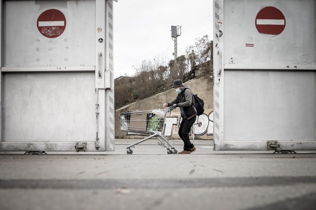 Ein Obdachloser transportiert seine Habseligkeiten in einem Einkaufswagen durch die Stadt