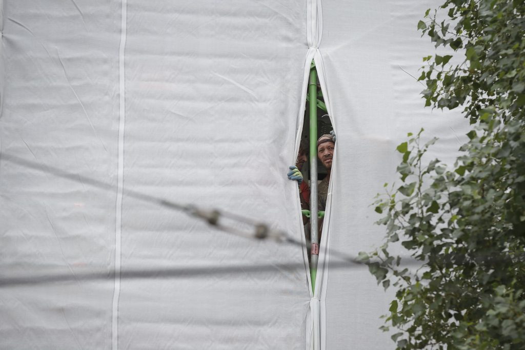 Bauarbeiter blicken hinter einer Gerüstverkleidung hervor