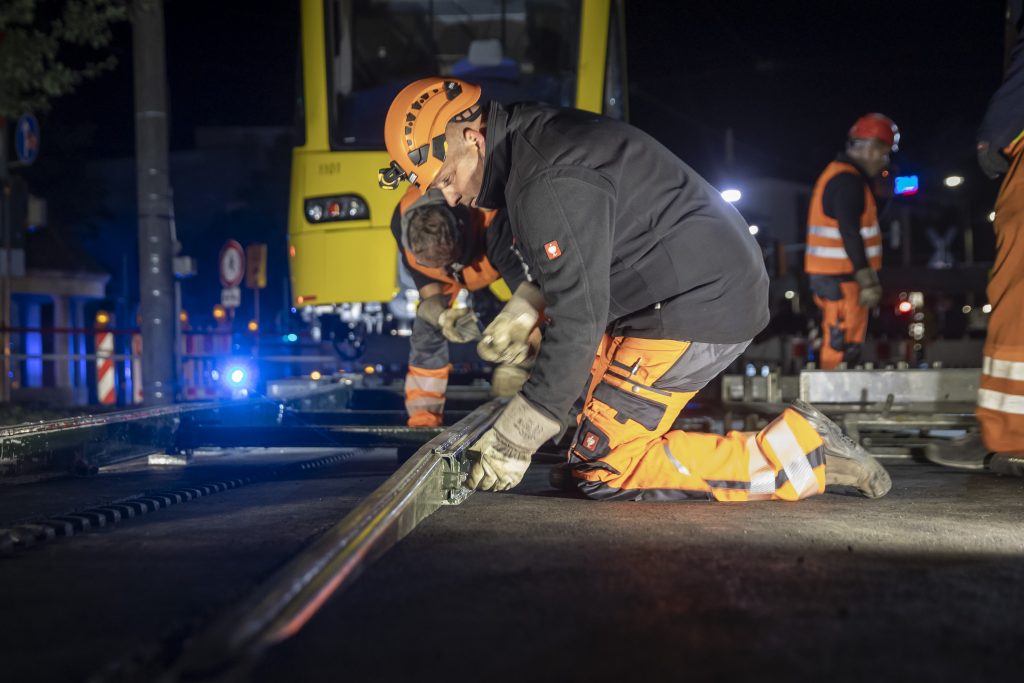 Arbeiter bereiten das aufgleisen eines Zugs von einem Tieflader auf Schienen vor