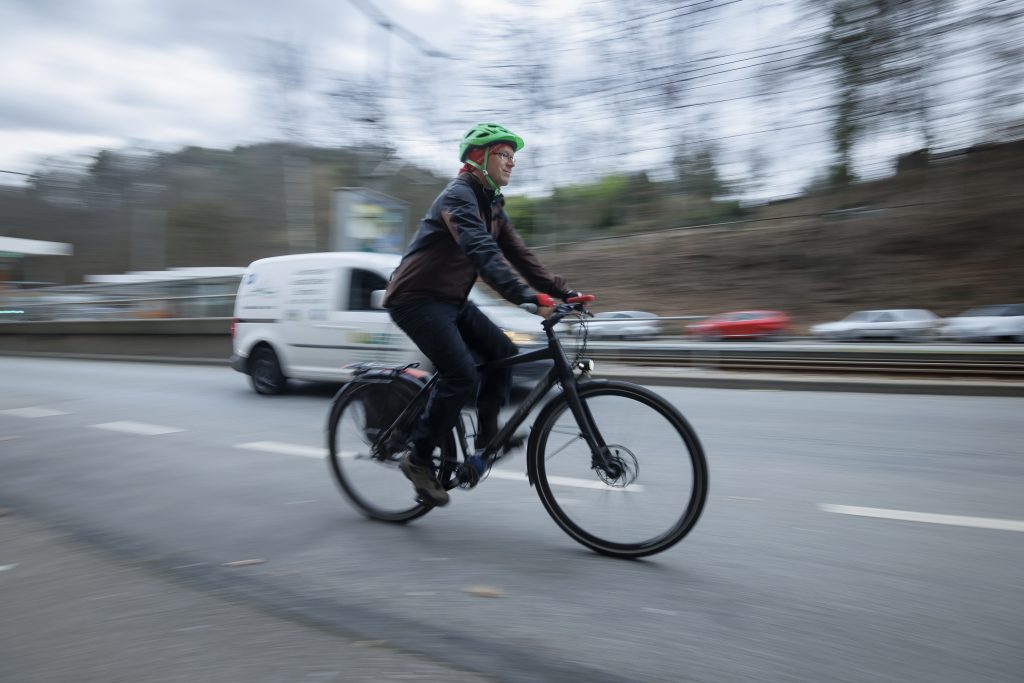 Ein Radfahrer fährt auf einem Schutzstreifen bergauf. Hintergrund ist eine Geschichte über ein Überholverbot von Fahrrädern.
